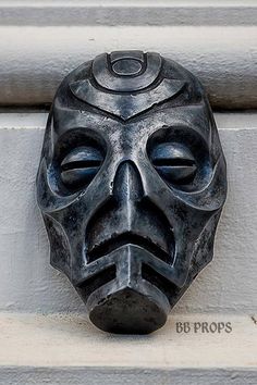 a black mask mounted to the side of a building