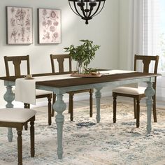 a dining room table with chairs and a chandelier hanging from the ceiling above it