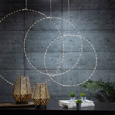 three vases sitting on top of a table next to a wall with lights hanging from it