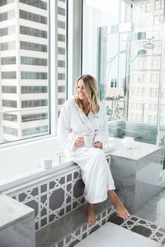 a woman sitting in a bathrobe holding a cup