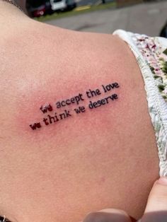 a woman's back with a tattoo that reads, i accept the love we think we