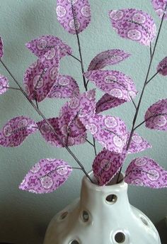 a white vase filled with purple flowers on top of a table