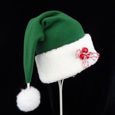 "Novelty green fleece Santa hat is decked out with a few red jingle bells and a candy cane striped yarn bow to add a festive touch to this classic hat. The fabric is a warm cozy green poly fleece and the trim is a white soft faux Sherpa fur. There is a snowy white faux fur pompom stitched on the top of the hat and the fur trim is accented with 3 red jingle bells. Hat is a slouch cone styling with generous sizing between 24-25\" circumference and a length of 19\". If you need more hats than this Green Winter Costume Hats And Headpieces, Green Mini Cap For Winter, Green Winter Mini Cap, Winter Green Mini Cap, Green Tinsel, Novelty Hats, Jingle Bell, Santa Claus Hat, Candy Cane Stripes