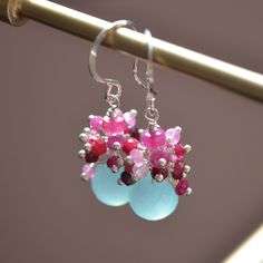 This is a made-to-order listing with a lead time of approx. 2-3 weeks from time of purchase. Please contact me prior to purchase if you have any concerns about the shipping date.  These genuine ruby earrings contain clusters of tiny red and pink rubies, grouped on top of blue chalcedony gem stones. I love this unexpected colour combination. The chalcedony stones are about 8mm in width and are a pretty shade of aqua. They almost seem to glow from within. Graceful sterling silver earwires complete this lovely pair of earrings. Ruby is the birthstone for July, and these make a wonderful birthday gift! Earrings are approx. 1 3/8" (35mm) long from the top of the earwire to the bottom of the chalcedony.  The gold pair seen in my photos is sold separately. Your jewellery will be packaged in a sma Handmade Sterling Silver Cluster Earrings For Anniversary, Red Dangle Jewelry With Gemstone Accents, Unique Ruby Multi-stone Jewelry, Red Sterling Silver Jewelry With Gemstone Accents, Red Gemstone Accented Drop Earrings, Red Teardrop Natural Stone Jewelry, Red Round Stone Earrings, Gemstone Dangle Cluster Earrings As Gift, Red Natural Stones Drop Earrings