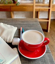 a cup of coffee on a saucer next to an open notebook and pencils