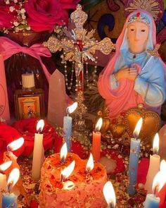 a table topped with candles and a cake covered in frosting next to a statue