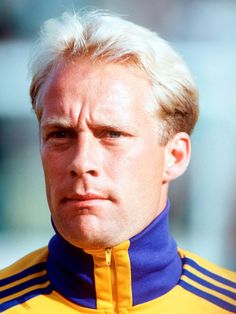 a man with blonde hair wearing a yellow and blue jacket