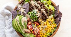 a wooden bowl filled with lots of different types of food on top of a table