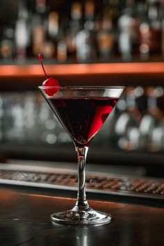 a red drink in a martini glass with a cherry on the rim