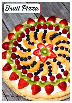 a pizza with fruit on it sitting on top of a wooden table