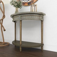 a clock on the wall next to a small table with a vase and flowers in it