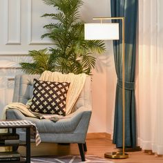 a living room with a couch, chair and lamp on the floor next to a potted plant