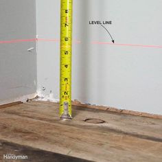 a measuring tape sitting on top of a wooden floor next to a hole in the wall