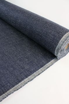 a roll of denim fabric on a white surface