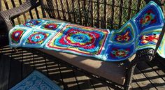 a crocheted blanket sitting on top of a bench