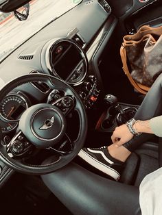 a woman is sitting in the driver's seat of a car with her hand on the steering wheel