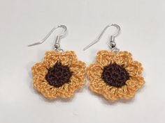 crocheted earrings with brown and yellow flower on them, hanging from silver earwires