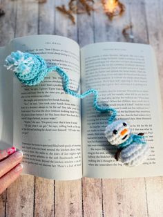 a crocheted snowman ornament on an open book with string attached to it