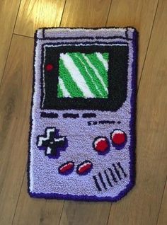 a rug with an old school video game controller on it's side, sitting on a wooden floor