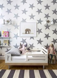 a child's bedroom with stars painted on the wall, and a bed in front of it