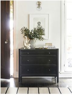 a black dresser sitting in the corner of a living room next to a wooden door