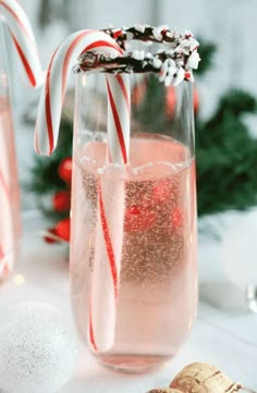 two glasses filled with liquid and candy canes on top of a table next to christmas decorations