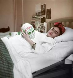 a woman laying in bed with a skull mask on her face and the head of a skeleton