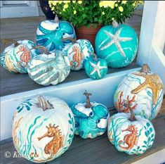 painted pumpkins with sea creatures on them are sitting on the front steps in front of a potted plant