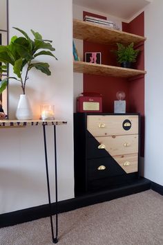 a black and white dresser sitting next to a shelf filled with books on top of a carpeted floor