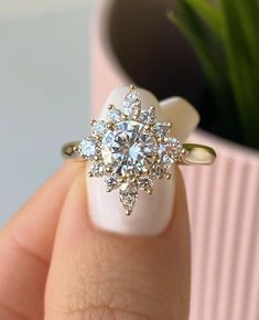 a close up of a person's hand holding a ring with a flower on it