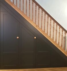 an empty room with wooden stairs and black cabinet under the bannister area on the second floor