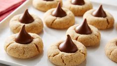 some cookies with chocolate on top are sitting on a white plate and ready to be eaten