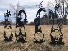 three metal sculptures in the shape of animals on grass with trees and houses in the background