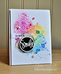 a handmade card with the word smile on it and an ink splattered background