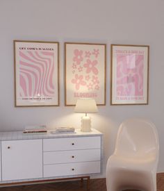 a white chair sitting next to a table with a lamp on it in front of two pictures