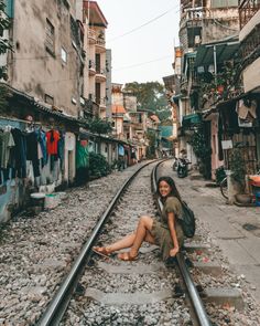 a woman sitting on train tracks in an alleyway