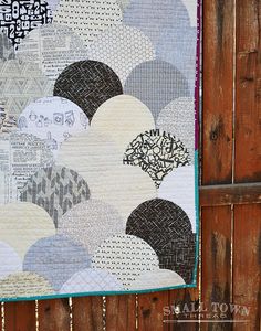 a quilt hanging on the side of a wooden fence