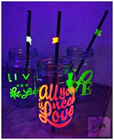 three mason jars with neon writing on them and straws in the bottom one is empty