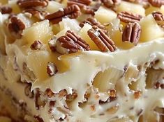 a close up of a cake with pecans and cream frosting on the top