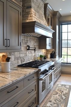 a kitchen with granite counter tops and stainless steel oven hoods, along with an area rug on the floor