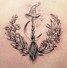 a woman's back tattoo with flowers and a wizard hat on top of it