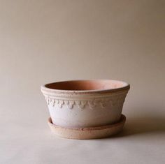 a white bowl sitting on top of a table next to a brown cup with a saucer