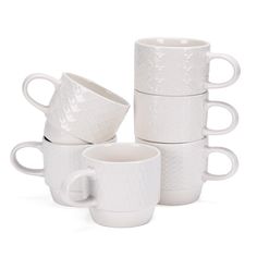 four white coffee cups stacked on top of each other in front of a white background