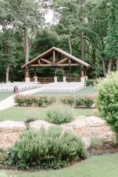 an outdoor wedding venue with white chairs and greenery