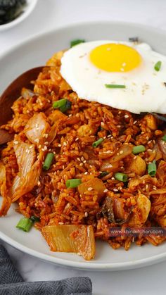 a plate with rice, meat and an egg on top is sitting on a table