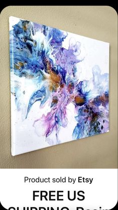 a painting hanging on the wall with blue, purple and white paint splattered