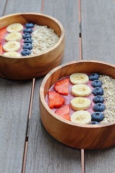 two wooden bowls filled with fruit and oatmeal on top of a table