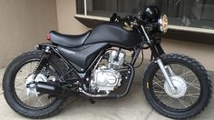 a black motorcycle parked in front of a building next to a window on the sidewalk