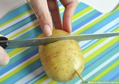 a person cutting up a potato with a pair of scissors on a striped table cloth