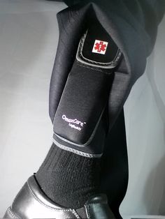 a person's foot wearing black shoes with red cross on the soles and socks